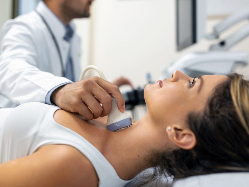 Close up shot of young woman getting her neck examined by doctor using ultrasound scanner at modern clinic
